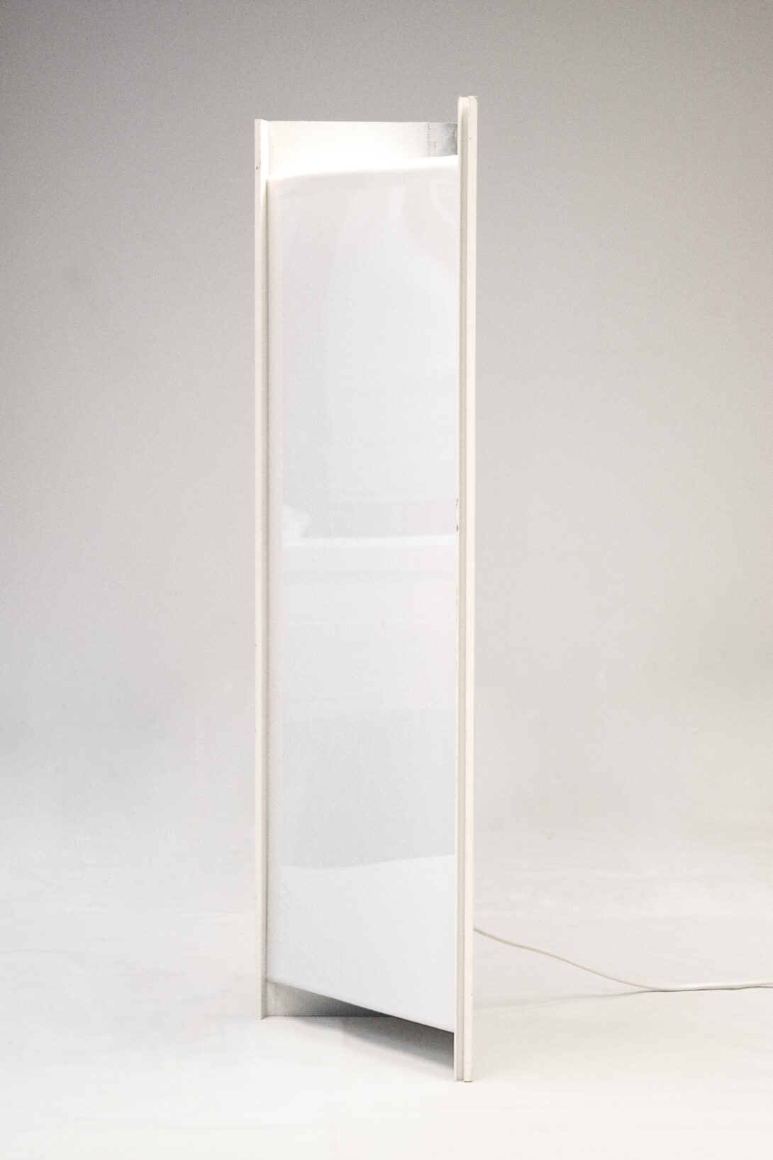 a vertically standing lamp made out of a white aluminium profile and a bent acryl plate on a white background